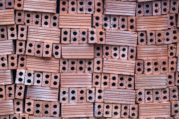 A close up of a pile of unused orange coloured bricks for use in construction.