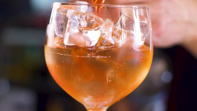 The process of making cocktail aperol spritz. pours orange liquor into glass