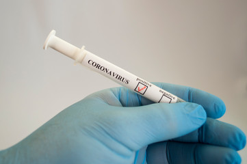 Naklejka premium A hand in a medical glove holds a test tube with tests on covid-19
