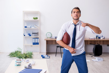 Young male employee throwing rugby ball in the office