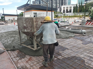 Group of construction workers pouring wet concrete using the mobile crane bucket the construction site.  
