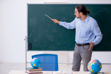 Young male geography teacher in front of blackboard