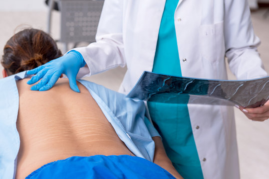 Young back injured man visiting female doctor chiropractor