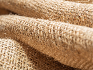 Crumpled burlap fabric, an abstract background, close up view. Texture of brown sackcloth. Crumpled baline. Selective soft focus. Blurred background