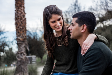 young couple in their pre-wedding session looking at each other. woman sitting on man and enjoying nature and her engagement outdoor