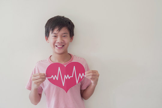 Mixed race child holding big red heart with cardiogram,  children health care, life insurance business concept, world heart day, world health day - Powered by Adobe
