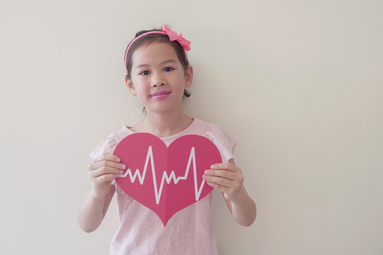 Mixed race child holding big red heart with cardiogram,  children health care, life insurance business concept, world heart day, world health day - Powered by Adobe