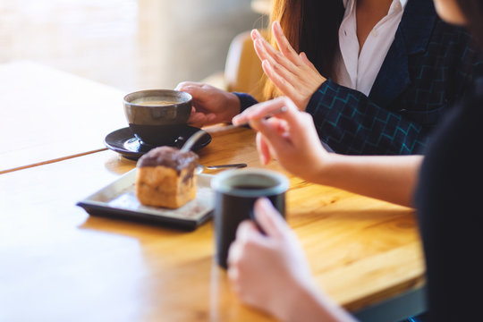 Closeup image of women enjoyed eating dessert and drinking coffee together in cafe