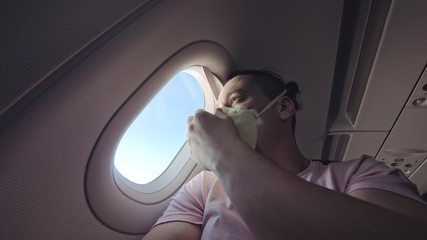 Man travel caucasian at plane with wearing protective medical mask. Male tourist at aircraft with protect respirator. Concept virus protection coronavirus pandemic sars-cov-2 covid-19 2019-ncov.