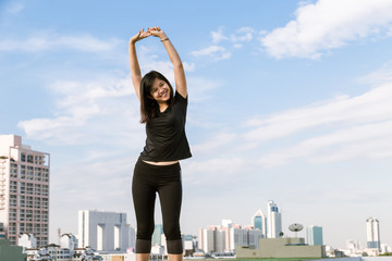 Fototapeta na wymiar Sport asian woman stretching exercise on top of building