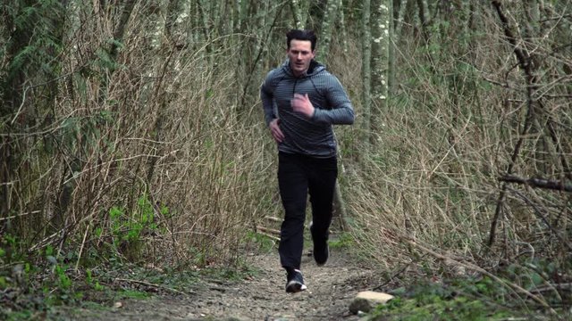 Determined Man Running Aggressively Uphill in Dramatic Forest Background