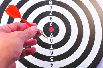 Red dart arrow hitting in the target center of dartboard