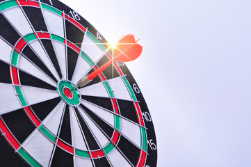 Red dart arrow hitting in the target center of dartboard