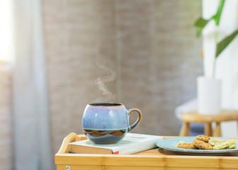 Bed tray table, with cup, cookies and a book.