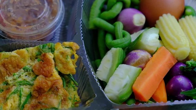 Traditional Thai food set of shrimp paste chili dip with acacia omelet and fresh vegetables in a plastic box.