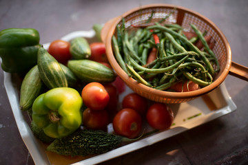 Fresh vegetables are piled up on a trey and small basket near a window with green natural background. Food, vegetables, home isolation and quarantine