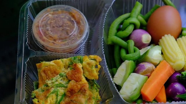 Traditional Thai food set of shrimp paste chili dip with acacia omelet and fresh vegetables in a plastic box.