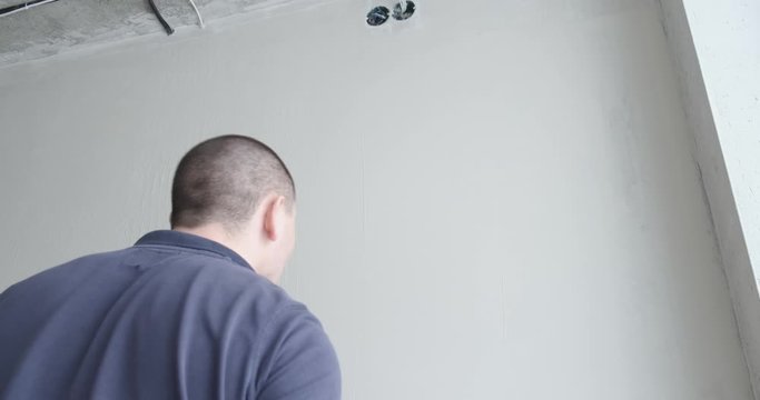 Repairman puts putty on wall for smooth texture. Smoothes out all irregularities. Properly prepared wall before wallpapering. Initial stage of repair work, dirty work, professional builder