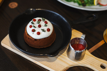 Chocolate lava cake top with whipping cream and goji berry with raspberry sauce on wooden dish in coffee shop.