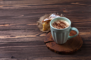Cup with coffee and apple pie on a rural wooden tabletop. Latte or cappuccino with chocolate sprinkles. Apple Charlotte. copy space