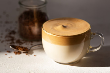 Cup of Dalgona coffee on a white table. Korean trendy sweet drink
