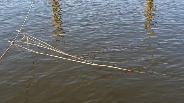 Somewhat long reefs lying in the surface of some water. the light shines down into the water. there are two poles that are reflected in the water