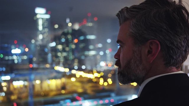 Closeup handsome ambitious bearded man entrepreneur office executive looking out of window to admire stunning night cityscape. Business people.