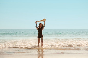 Rear view of beautiful asian young surfer girl with surfboard on a beach. Woman runs into the ocean with surfboard. Sporty people having fun in sunny day - Extreme sport, travel and vacation concept.