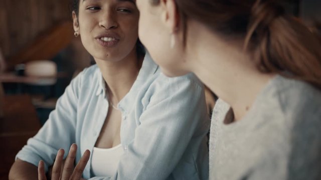 Happy female friends in a coffee shop on a weekend. Two women sitting at a coffee table talking and smiling. 
