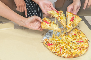 Hands taking pizza slices from wooden table, close up view. Group of people eating delicious pizza, Close-up of business people talking slice of pizza from the box. close friends eating pizza.