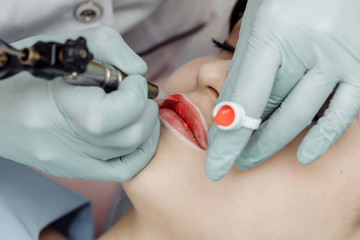 Woman having permanent makeup on lips in beauty salon
