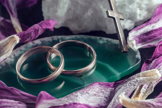 Two Intertwined Wedding Rings On A Green Stone.