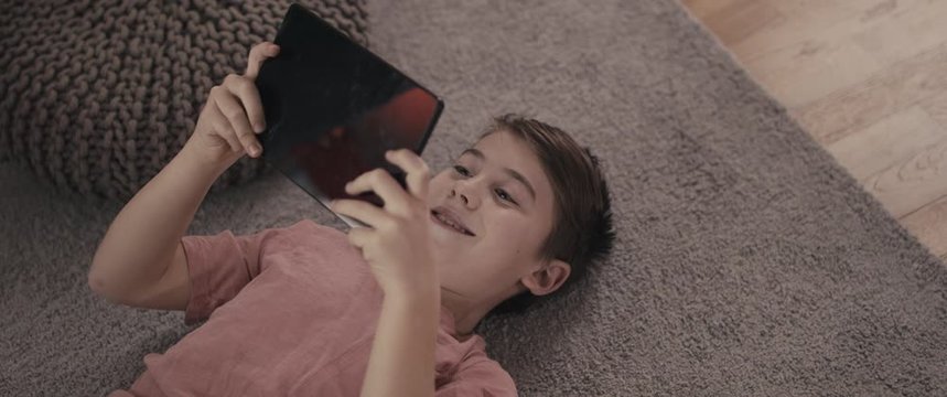 Boy enjoying remote learning and education on tablet during coronavirus covid 19 pandemic outbreak wellbeing staying home in isolation