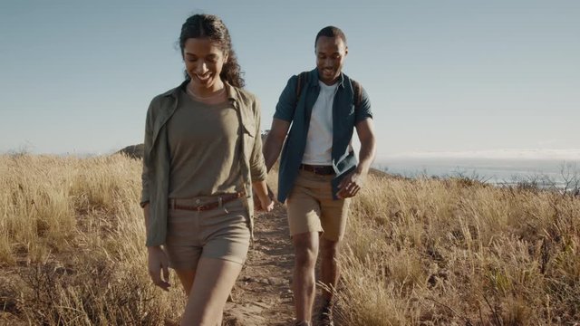 Couple walking through a country path on the mountain. Young man and woman hiker hiking in nature.
