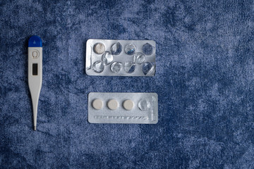 Thermometer and pills on blue background. Blank space for input the text 