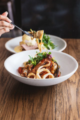 Hand pinching Spaghetti Seafood and lifted with a fork: Spaghetti with Prawns, Squids, Mussels Cooked in Olive Oil, Chillies and Garlic.