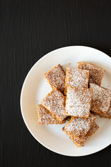 Homemade Tasty Applesauce Cake on a white plate on a black surface, top view. Flat lay, from above, overhead. Copy space.