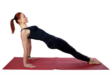 Pilates or yoga. A beautiful slender girl performs a reverse plank on the Mat. Isolated photo on a white background.