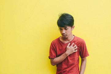 young man is expressing heart disease with a yellow background
