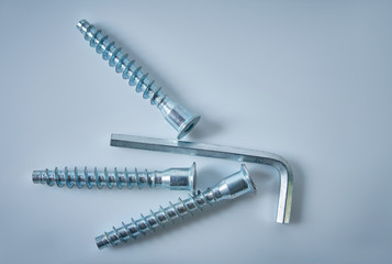 Hexagon wrench and screws are on a bright background. Assembly of furniture.