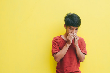 the young man in the red shirt coughed with an isolated yellow background
