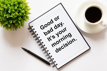 Note pad with Inspirational quote - Good or bad day it's your morning decision. Flat lay, coffee, pen and green plant