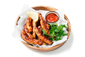 Delicious homemade baked sausages in a wooden plate isolated on white background