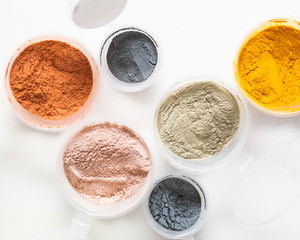 A top view of the dry pigments and powders in circle plastic jars on white background. Food and...