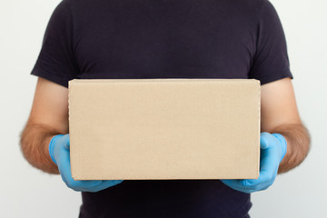 Delivery man holding cardboard boxes.Delivery by courier in medical rubber gloves. The shipping time during coronavirus. Mockup. Quarantine