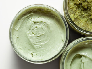 A natural ingredients body mousse in a jar on light background. Skin care, spa and clean cosmetic concept. Health and beauty. Homemade mask or cream with matcha and kale. Sea salt. Top view. Close-up.