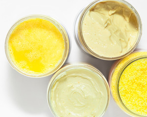 The body scrub, cream and bath sea salt with yellow natural aromatic ingredients in the jars on white background. Skin care, spa and clean cosmetic concept. Health and beauty. Top view