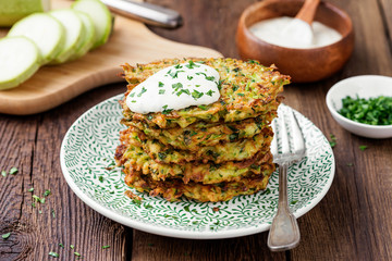 Zucchini fritters, vegetarian zucchini pancakes, served with fresh herbs and sour cream.
