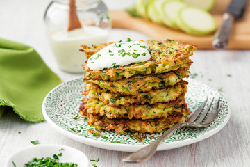 Zucchini fritters, vegetarian zucchini pancakes, served with fresh herbs and sour cream.