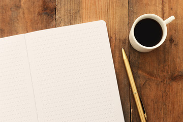 top view image of open notebook with blank pages next to cup of coffee on wooden table. ready for adding text or mockup